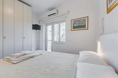 a white bedroom with a bed and a window at HYRIA Holiday Home in Rome
