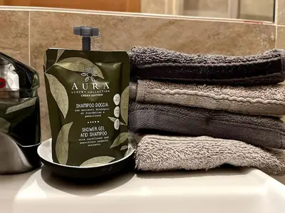 a pile of towels and a bottle of soap on a sink at Dreams Under the Trees - Metro Roma Termini in Rome