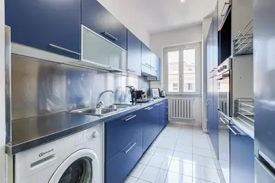 a kitchen with blue cabinets and a washing machine at Koma 7 Apartment in Rome