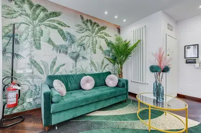 a green couch in a living room with a palm mural at Koma 7 Apartment in Rome