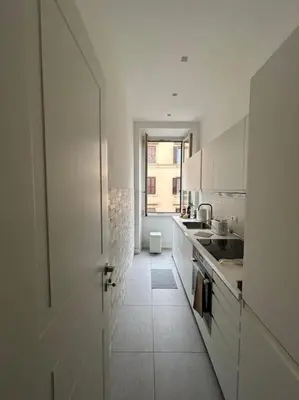 a white kitchen with a door open to a hallway at Appartamento Ostiense CasaFrai in Rome