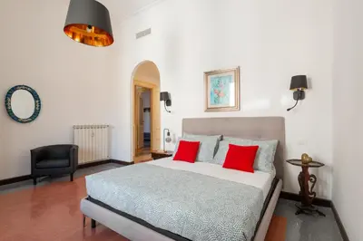 a bedroom with a bed with red pillows and a chair at La Stella Apartment by Hostand in Rome
