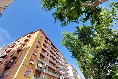 a tall yellow apartment building with trees in the foreground at On Rome Affittacamere o GuestHouse in Rome