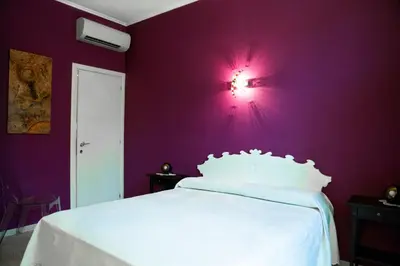 a bedroom with purple walls and a white bed at Violet House in Rome