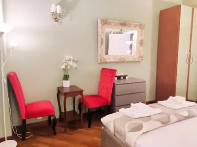a bedroom with two red chairs and a table and a mirror at Sina Rent Room Flaminio in Rome
