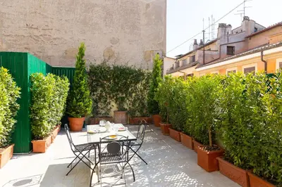 a patio with a table and chairs and potted plants at Amazing Domus Ruspoli in Rome