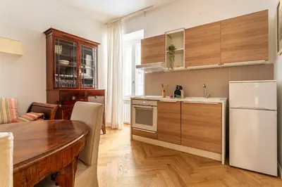 a kitchen with a table and a white refrigerator at iFlat A Peaceful Nest In The Eternal City in Rome
