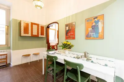 a dining room with a table and green chairs at Trieste Guesthouse - ZENO 48 in Rome