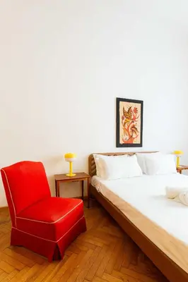 a bedroom with a bed and a red chair at Trieste Guesthouse - ZENO 48 in Rome