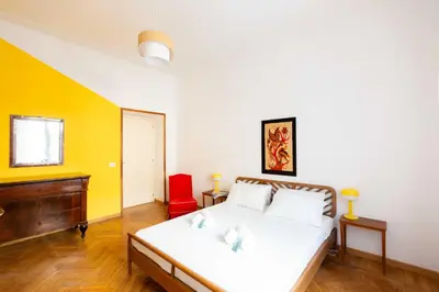 a bedroom with a white bed and a red chair at Trieste Guesthouse - ZENO 48 in Rome