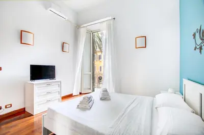 a white bedroom with a bed and a tv at Casa a San Giovanni - Charming Flat in Rome in Rome