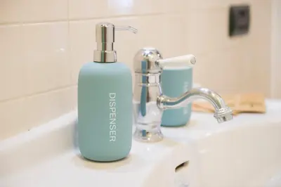 a blue bottle of soap sitting on a bathroom sink at Cacio e Pepe FLATS 1 & 2 in Rome