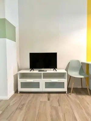a white dresser with a tv and a chair at Green House Rome in Rome