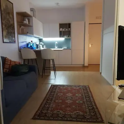 a living room with a blue couch and a kitchen at Monolocale nuova costruzione con giardino in Rome