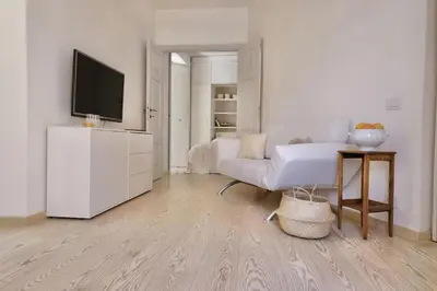 a white living room with a tv and a couch at Panoramic Quirinal Penthouse in Rome