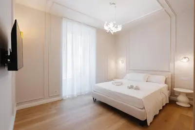 a white bedroom with a white bed and a chandelier at Firenze Boutique Rooms in Rome