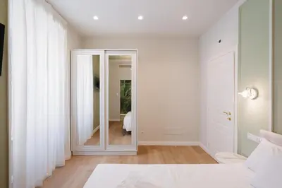 a white bedroom with a mirror and a bed at Firenze Boutique Rooms in Rome
