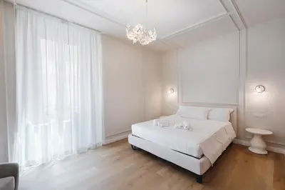 a white bedroom with a white bed and a chandelier at Firenze Boutique Rooms in Rome