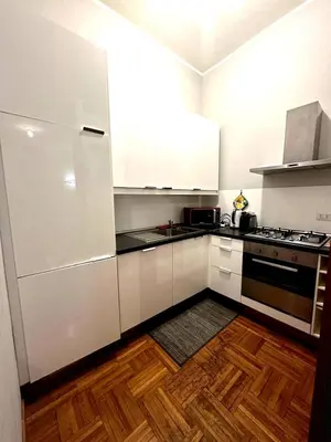 a kitchen with white cabinets and a wooden floor at Cerri apartment in Rome