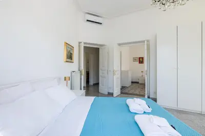 a white bedroom with two towels on a bed at Piazza Caprera - Family Apartment in Rome