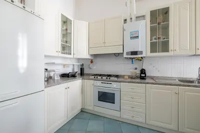 a kitchen with white cabinets and a stove top oven at Piazza Caprera - Family Apartment in Rome