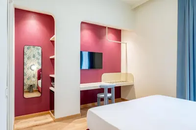 a room with a pink wall with a desk and a mirror at UNICO Suite - GRUPPO BLAM in Rome
