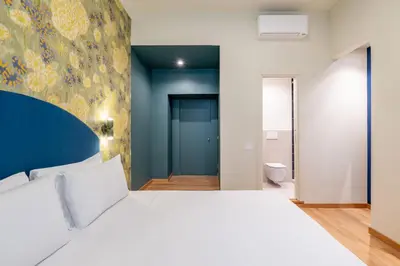 a bedroom with a white bed and a blue wall at UNICO Suite - GRUPPO BLAM in Rome