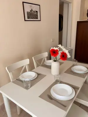 a white table with white plates and red flowers on it at DOMUS Laura VATICANO in Rome