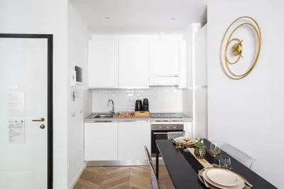a kitchen with white cabinets and a black counter top at Mazzini City Center Apartment - Vaticano - Foro Italico - Stadio Olimpico-Rai Delle Vittorie in Rome