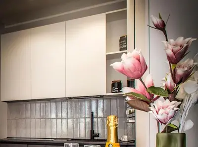 a kitchen with white cabinets and pink flowers in a vase at INTERNO 10 - Musei Vaticani in Rome