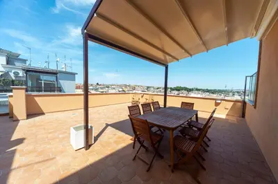 a patio with a wooden table and chairs on a roof at Cardinal Mistrangelo - next to the metro station, large and comfortable penthouse with terrace in Rome