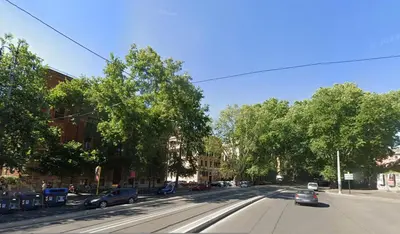 an empty street with cars driving down the street at Trasteverino in Rome