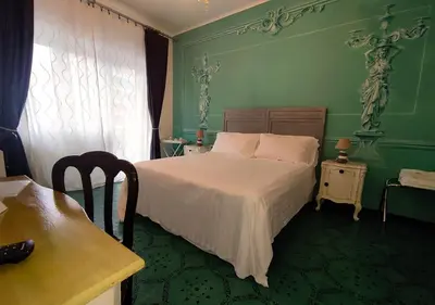 a green bedroom with a bed and a table at Gregory Place in Rome