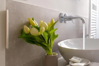 a vase with yellow flowers on a counter next to a sink at iFlat Discovering Monti - Charming and Modern apt in Rome