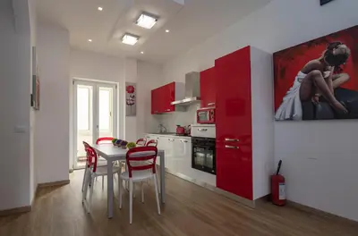 a kitchen with red cabinets and a table and chairs at rainbow al colosseo in Rome