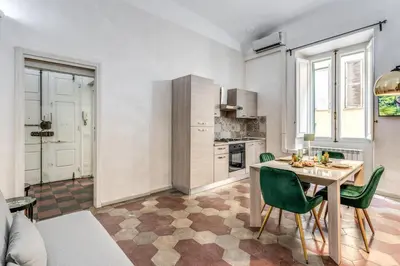a kitchen with a table and green chairs in a room at Casa Mecenate in Rome
