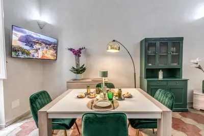 a dining room with a table and green chairs at Casa Mecenate in Rome
