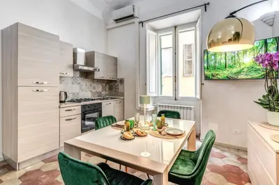 a kitchen with a table and green chairs in a room at Casa Mecenate in Rome