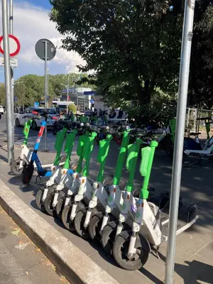 a row of green and white scooters parked on a street at Domus Provinciae in Rome