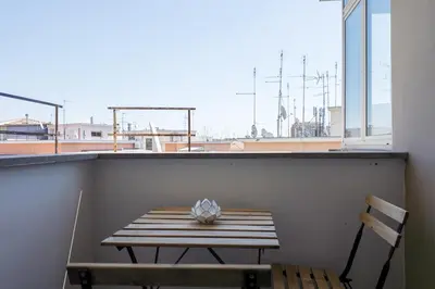 a table and a chair on a balcony with a window at Elegant Hideaway Steps from St Peter in Rome