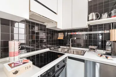 a kitchen with white cabinets and black tiled walls at Elegant Hideaway Steps from St Peter in Rome