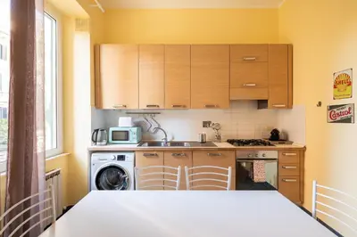 a kitchen with wooden cabinets and a washer and dryer at Rétro Chic Circo Massimo in Rome