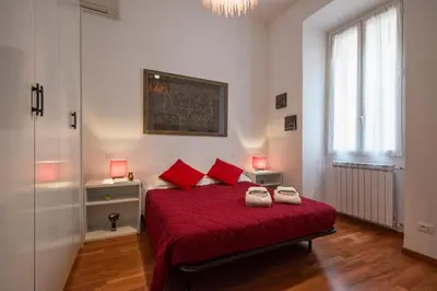 a bedroom with a bed with red sheets and red pillows at Cozy apartment in Esquilino in Rome