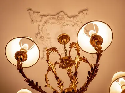 a gold chandelier with three lights on a wall at Alla Basilica Rooms in Rome