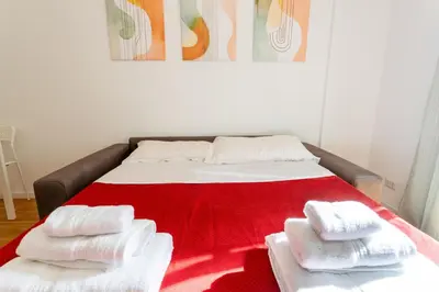 a bed with towels on it with a red blanket at 