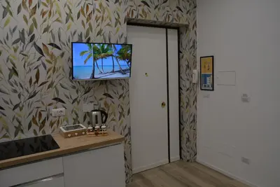 a room with a tv on a wall with a kitchen at Casa Amabile in Rome
