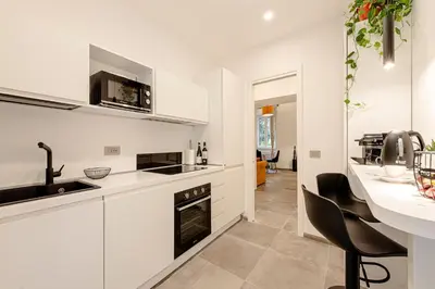a kitchen with white cabinets and a sink and a counter at 24VaticanSuite in Rome