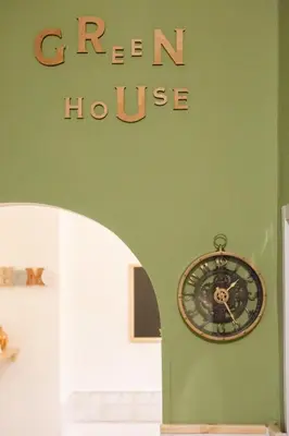 a clock on a green wall with a green house at Green house in Rome