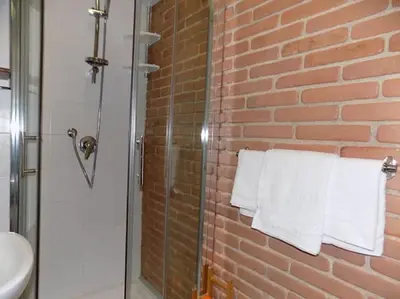 a bathroom with a glass shower with towels on a brick wall at Il Giardino del Viaggiatore in Rome
