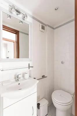 a white bathroom with a sink and a mirror at Aurelia 386 Vatican House in Rome